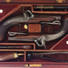 A PAIR OF IRISH PERCUSSION TRAVELLING PISTOLS BY TRULOCK & SONS, DUBLIN, CIRCA 1830 with signed browned twist sighted barrels, engraved case-hardened breeches, engraved case-hardened breech tangs, signed back-action locks engraved with border ornament and foliage, figured walnut full stocks, chequered butts, engraved blued steel mounts including trigger-guards with pineapple finials, stirrup ramrods, and vacant silver escutcheons: in original mahogany case lined in plum velvet, complete with some accessories including powder-flask (one compartment lid replaced, case lining faded, bullet mould associated) 19cm; 7 1/2in �2200-2500